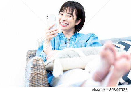 ソファでスマホを使う若い女性 86397523