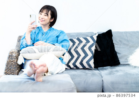ソファでスマホを使う若い女性 ソファでスマホを使う若い女性 86397534