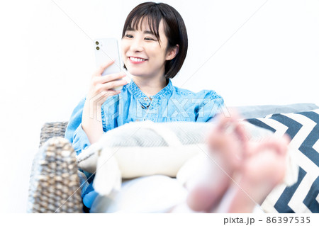 ソファでスマホを使う若い女性 86397535