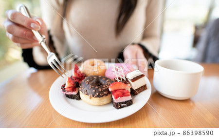沢山のスイーツを食べる女性 86398590