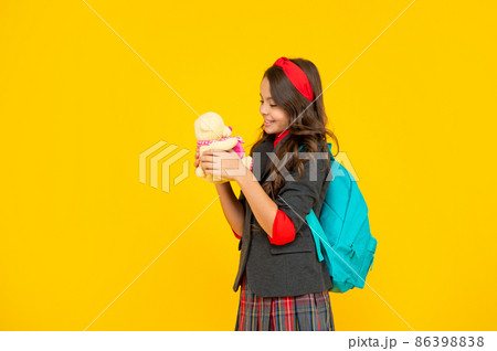 positive kid in uniform on yellow background. september 1. happy childhood. child with toy. 86398838
