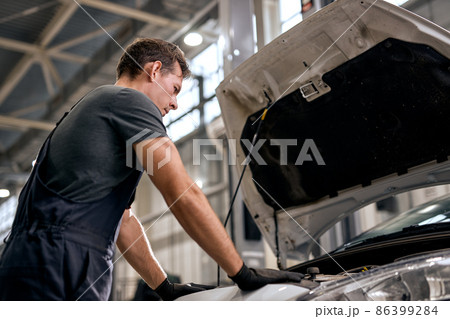 professional male car service worker repairing vehicle, stand by opened car hood 86399284