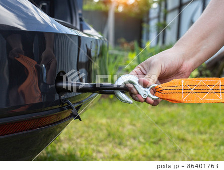 A man's hand clings a tow rope to a tow hook in a passenger car, close-up. Summer 86401763