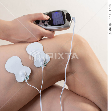 Electrodes of modern acupuncture and anti-cellulite massagers on the legs of a girl in problem areas. Home physiotherapy, close-up 86401780