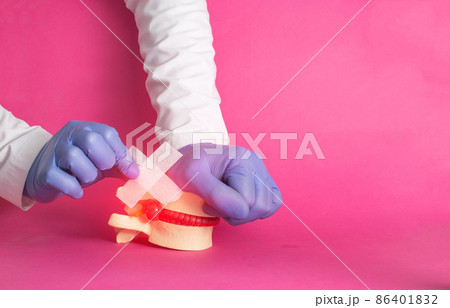 The doctor's hands are gluing a medical plaster on the released nucleus pulposus, intervertebral hernia, pink background. Spondylolisthesis and spondoarthrosis treatment concept, copy space for text 86401832