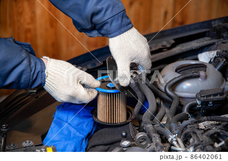 A mechanic takes out an old, dirty fuel filter after refueling with low-quality fuel. Car maintenance, close-up 86402061
