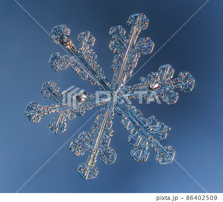 Snowflake on smooth gradient background. Macro photo of real snow crystal on glass surface. This is small snowflake with unusual pattern. 86402509
