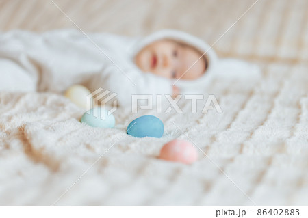 Cute smile happy little baby in white rabbit costume, playing with colorful easter eggs 86402883
