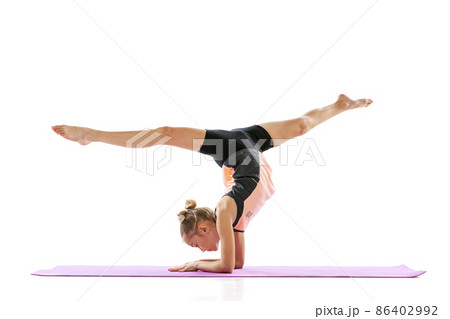 Little flexible girl, rhythmic gymnastics artist isolated on white studio background. Grace in motion, action. Doing exercises in flexibility. 86402992