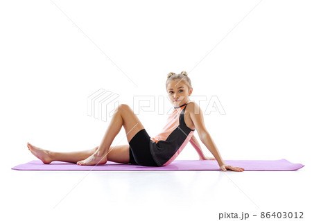 Portrait of little beautiful girl, gymnast, kid doing morning exercises isolated on white studio background. Flexibility, health, activity Portrait of little beautiful girl, gymnast, kid doing morning exercises isolated on white studio background. Flexibility, health, activity 86403012