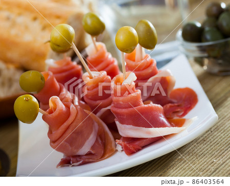 Traditional Spanish tapas - rolls of ham served with green olives 86403564