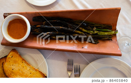 Calcots onions served on plate with Romesco sauce - traditional Catalan dish 86403840