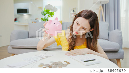 woman shakes piggy bank 86405079