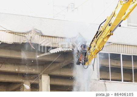 老朽化した公共建造物の解体作業をする重機 86406105