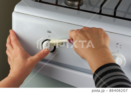 Female hands wash the taps of the white gas stove with a toothbrush. An unusual way of home cleaning 86406207