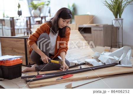 young asian female assembling furniture on her own young asian female assembling furniture on her own 86406252