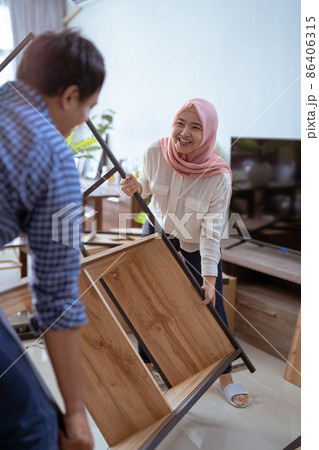 couple carrying new furniture together at their house couple carrying new furniture together at their house 86406315