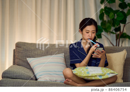 深夜スマホを見ながら歯磨きをする女性 86406754