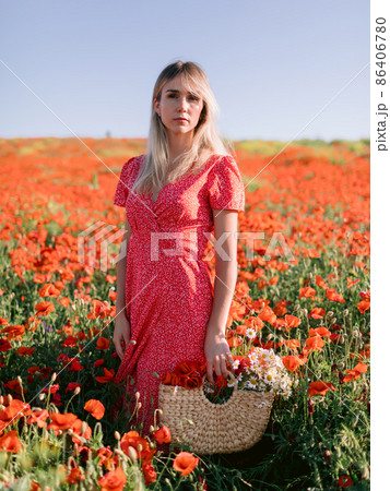 Caucasian blonde woman in a poppy field. Woman in red dress and handbag with wild flowers Caucasian blonde woman in a poppy field. Woman in red dress and handbag with wild flowers 86406780