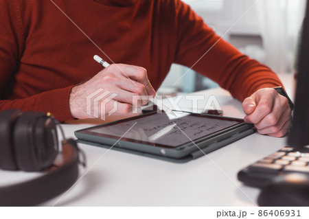 man works at home, takes notes in an electronic tablet with stylus man works at home, takes notes in an electronic tablet with stylus 86406931