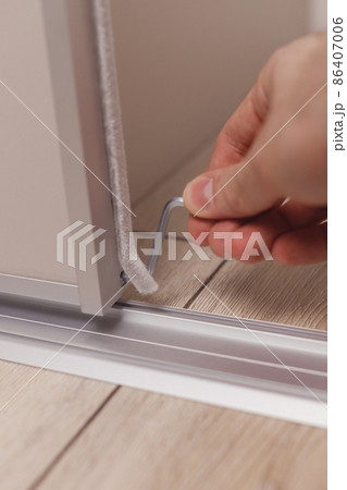 Handyman adjusts a sliding wardrobe door with a hex key at home 86407006