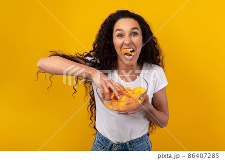 Excited Latin Lady Eating Delicious Potato Crisps Excited Latin Lady Eating Delicious Potato Crisps 86407285