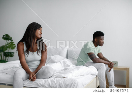 Sad young african american woman look at offended guy on white bed in bedroom interior 86407572