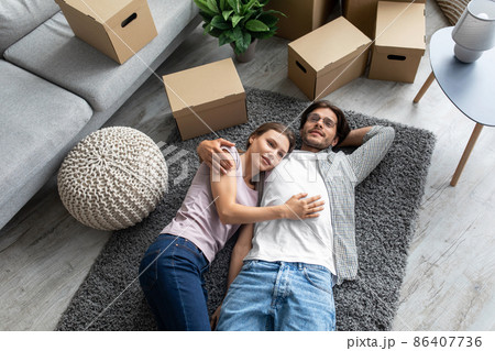 Tired smiling european millennial husband and wife rejoice buying new own apartment, lie on floor 86407736