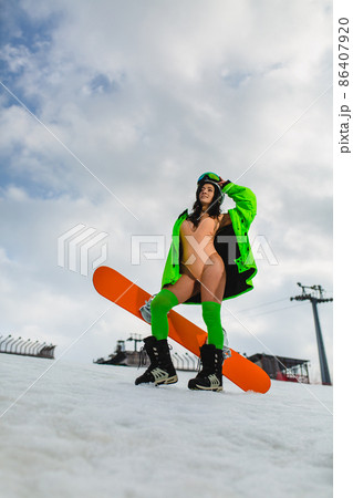 Young beautiful woman posing with a snowboard on a ski slope 86407920