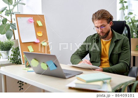 Young man office worker concentrated on work, writing documents information, sit alone 86409101
