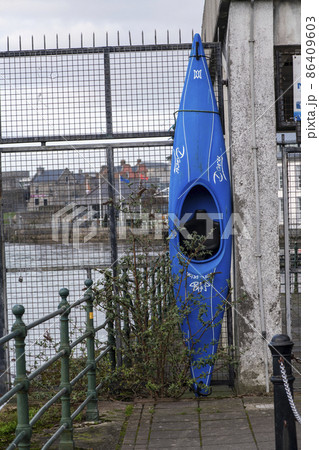 A blue water kayak parked vertically on a fence 86409603