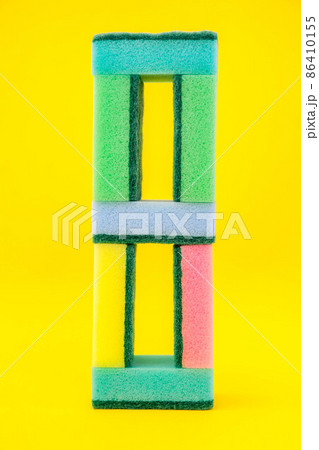 Multicolored sponges for cleaning folded pyramid on a yellow background. Space for text Multicolored sponges for cleaning folded pyramid on a yellow background. Space for text 86410155