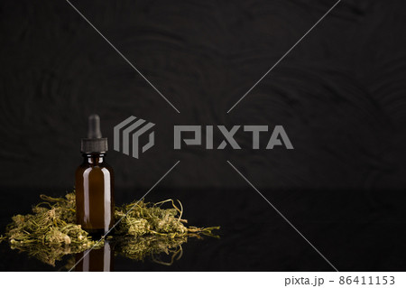 Medicinal CBD oil from cannabis. Bottle with medicinal marijuana extract on black background. CBD Cannabis Formula. Medicinal CBD oil from cannabis. Bottle with medicinal marijuana extract on black background. CBD Cannabis Formula. 86411153