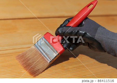 Painting or staining wooden terrace floor. Red brush, close-up. Painting or staining wooden terrace floor. Red brush, close-up. 86411516