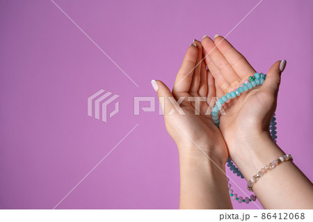 Woman holds in hand rosary or mala beads strand used for keeping count during mantra meditations Woman holds in hand rosary or mala beads strand used for keeping count during mantra meditations 86412068