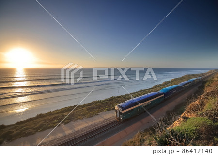 夕暮れ時、サンディエゴの海岸線を走るアムトラックの列車 86412140