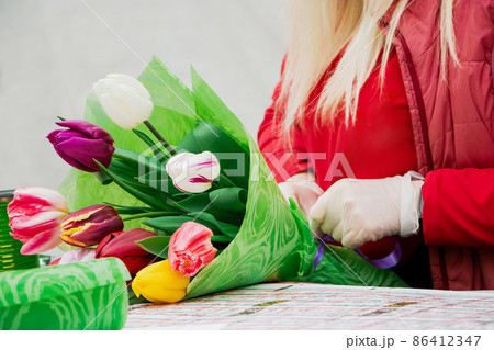 Woman florist makes bouquet of tulips. Hands hold multi-colored spring flowers. Small business concept, flower market. Woman florist makes bouquet of tulips. Hands hold multi-colored spring flowers. Small business concept, flower market. 86412347