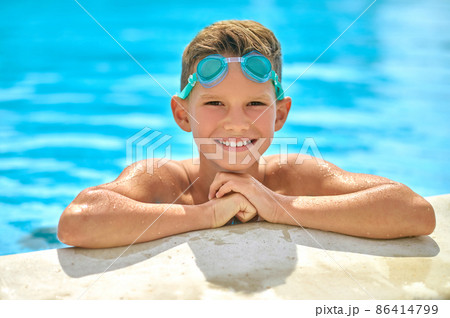 Boy peeking out of pool looking at camera Boy peeking out of pool looking at camera 86414799