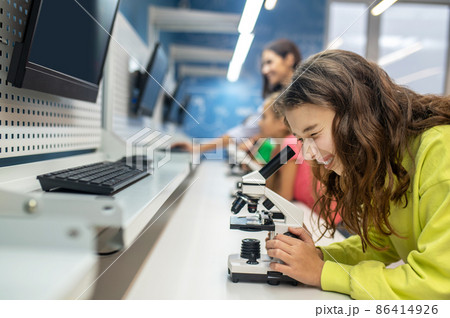 Girl sideways to camera looking into microscope with interest 86414926
