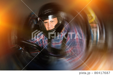 Portrait of male racer in helmet driving kart on track 86417687