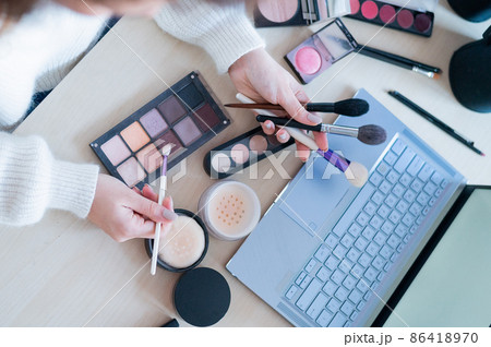 A faceless woman watches online training from a professional makeup artist on a laptop. Distance learning 86418970
