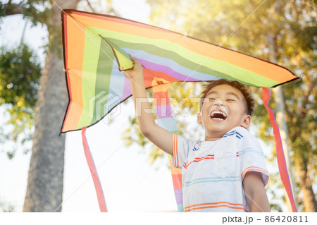 Asian happy children boy with a kite running to fly on in park 86420811
