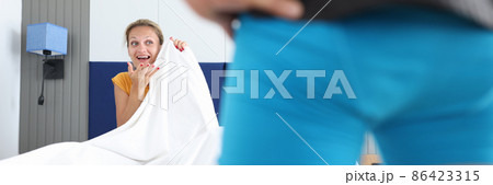 Woman sitting on bed looks at man in shorts closeup Woman sitting on bed looks at man in shorts closeup 86423315