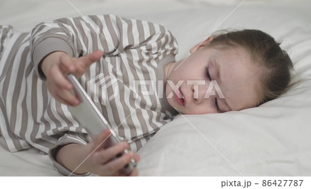 Child uses smartphone touch screen for education in bed 86427787