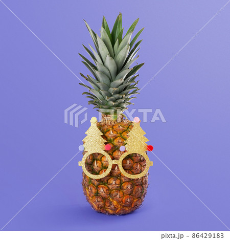 Pineapple in sunglasses on very peri color background. New Year and Christmas creative concept. Pineapple in sunglasses on very peri color background. New Year and Christmas creative concept. 86429183