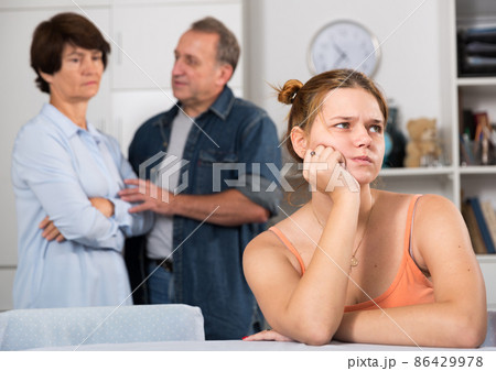 Upset female is sitting at the table and her parents are sympathying with her 86429978