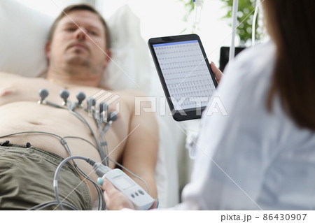 Doctor taking cardiogram to patient on couch in clinic closeup 86430907