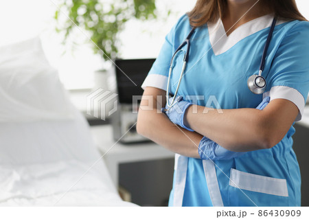 Woman doctor with crossed arms standing in hospital ward closeup Woman doctor with crossed arms standing in hospital ward closeup 86430909