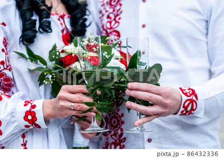 Newlyweds hold a wedding bouquet of roses and glasses of champagne Newlyweds hold a wedding bouquet of roses and glasses of champagne 86432336