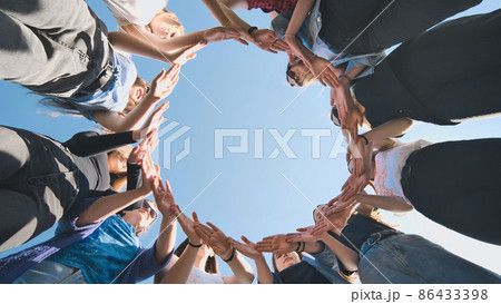 A group of girls makes a circle from their palms. 86433398
